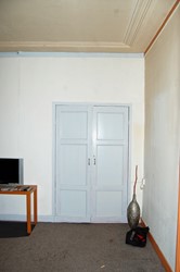 <p>De dubbele deuren van een in het voorhuis uitgebouwde inloopkast waren oorspronkelijk opgenomen in de wandbespanning. Later zijn deze omgedraaid zodat de van panelen voorziene achterzijde in het zicht kwam. </p>
